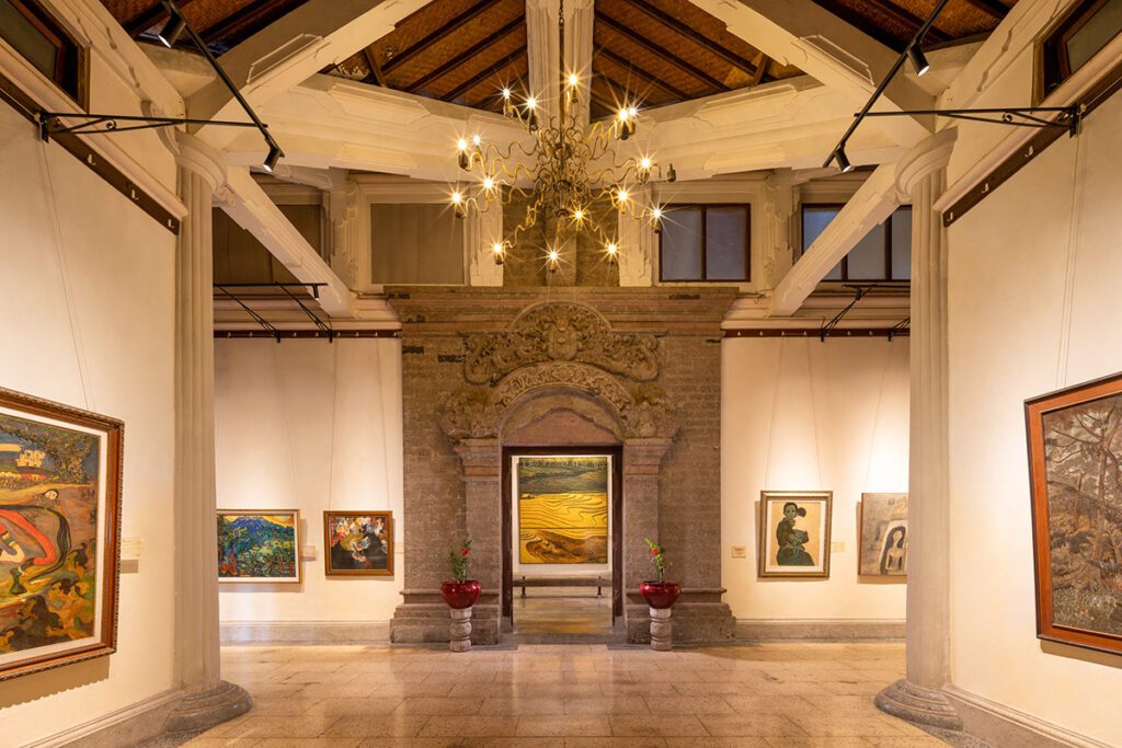 Interior of the Agung Rai Museum of Art (ARMA) displaying traditional Balinese paintings and classic architecture