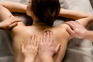 Close-up of two therapists' hands performing a synchronized four hands massage on a client's back at Jaens Spa Ubud, Bali.