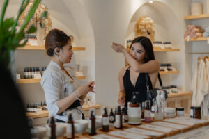 tamu wanita sedang memilih dan menguji aroma minyak esensial di rak produk aromaterapi Jaens Spa Ubud