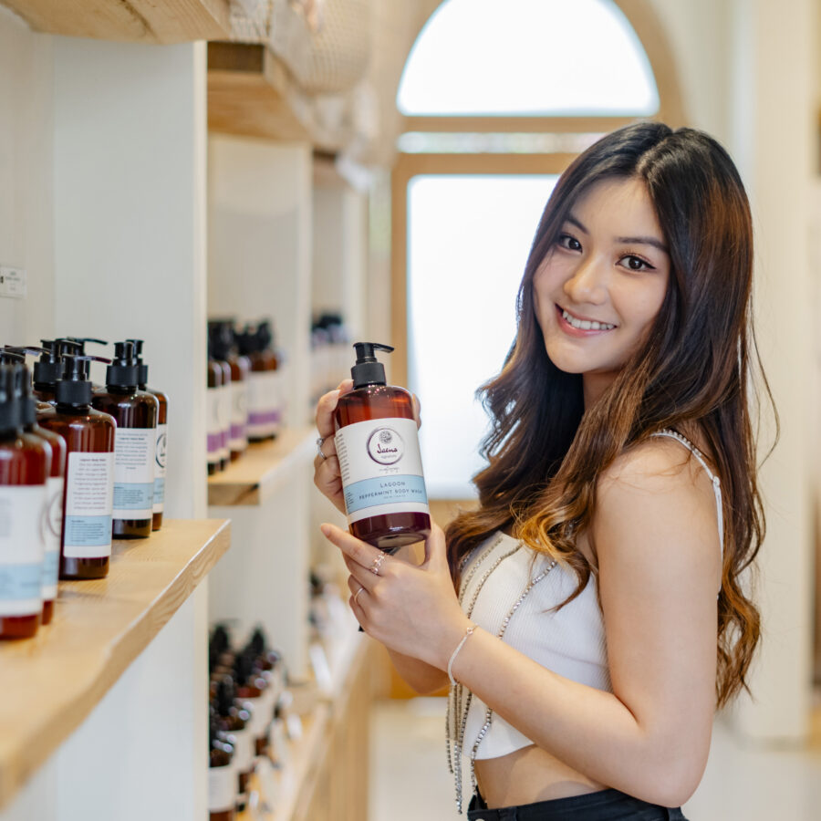 A smiling female guest showcasing an exclusive body care product bottle from Jaens Spa Ubud after enjoying this month's spa bali promo.